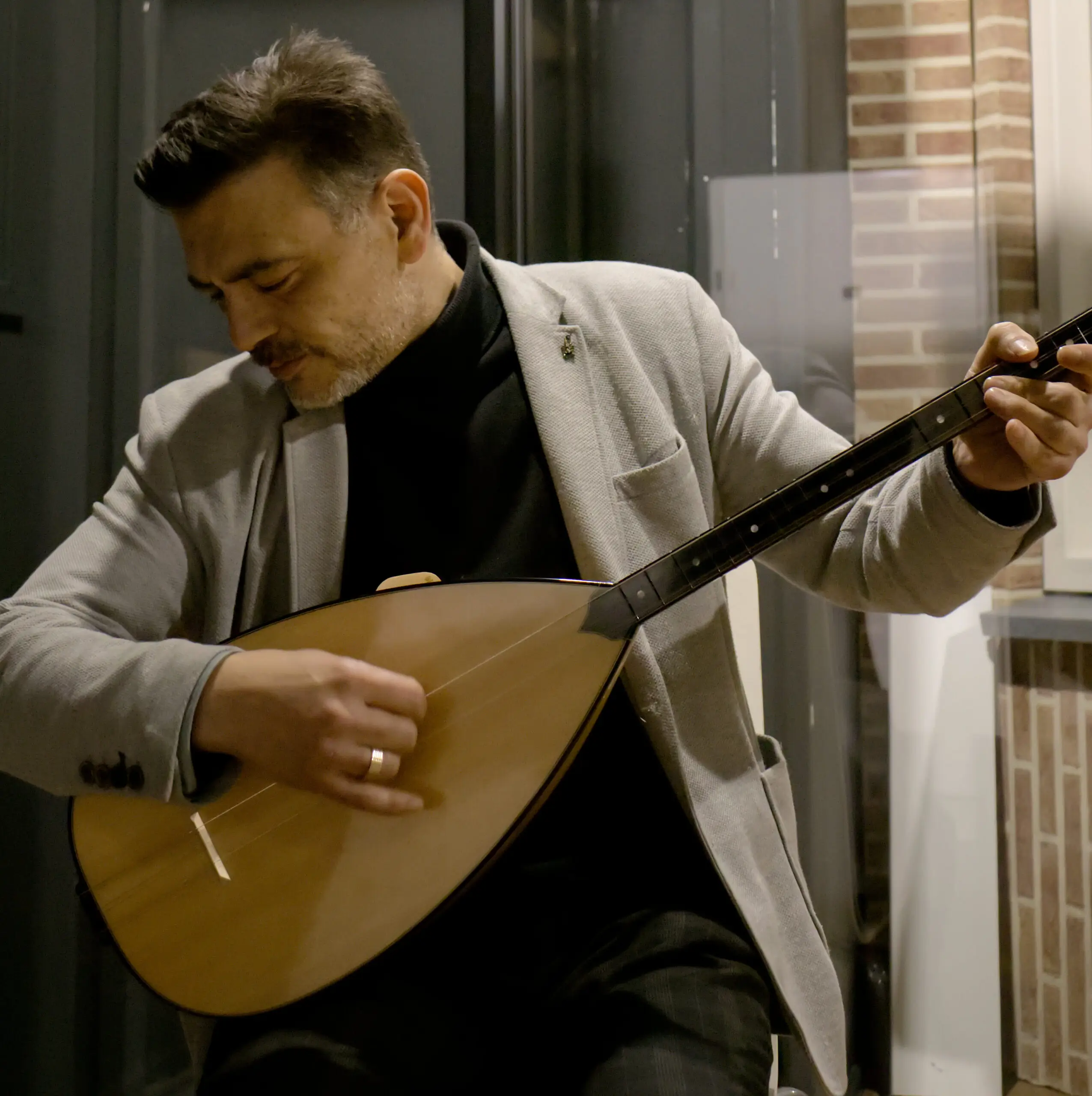 Foto waar Mesut met baglama zit te spelen