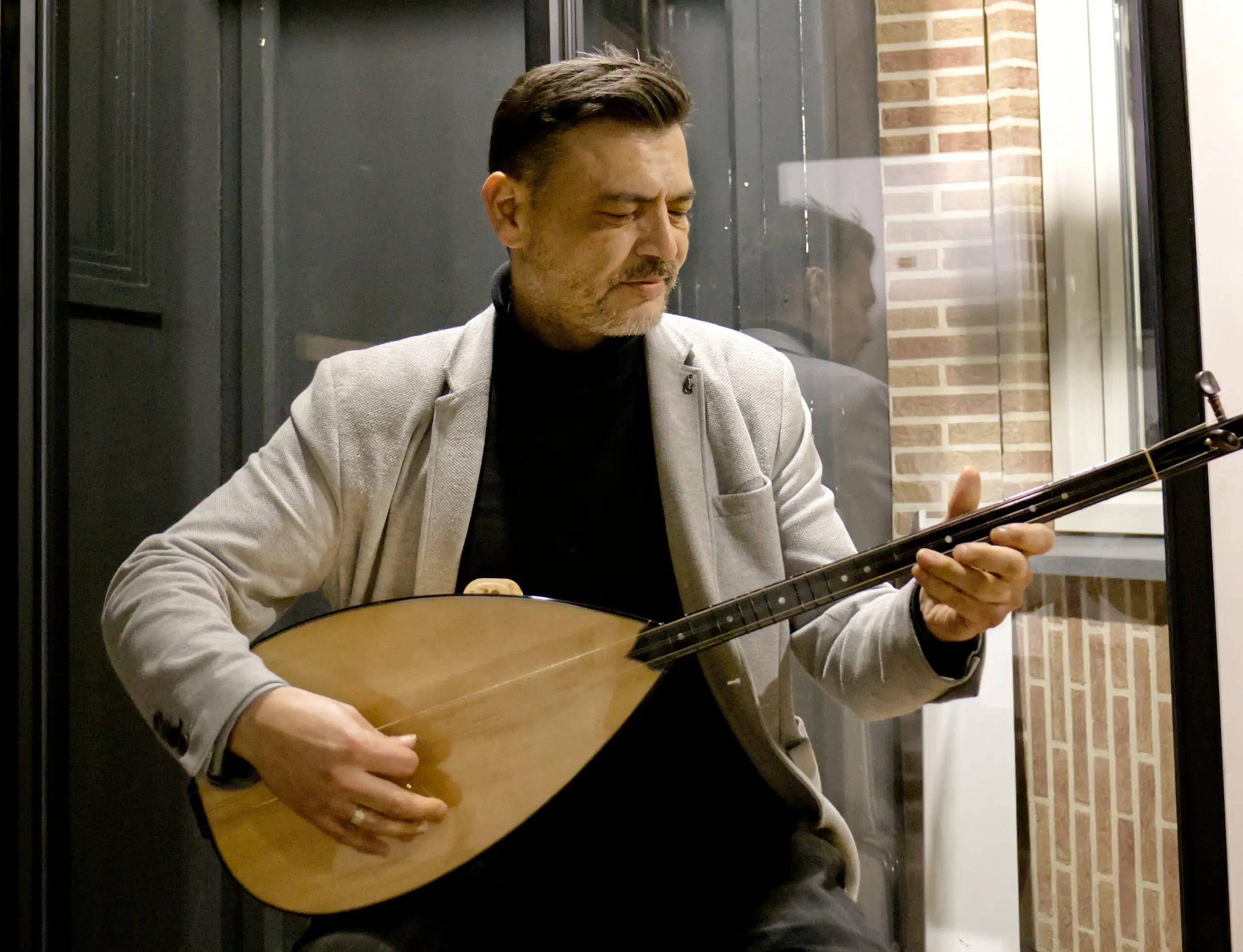 Foto waar Mesut met baglama zit te spelen